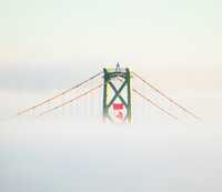 Bridge up right viewed through fog with Canadian flag hanging from it